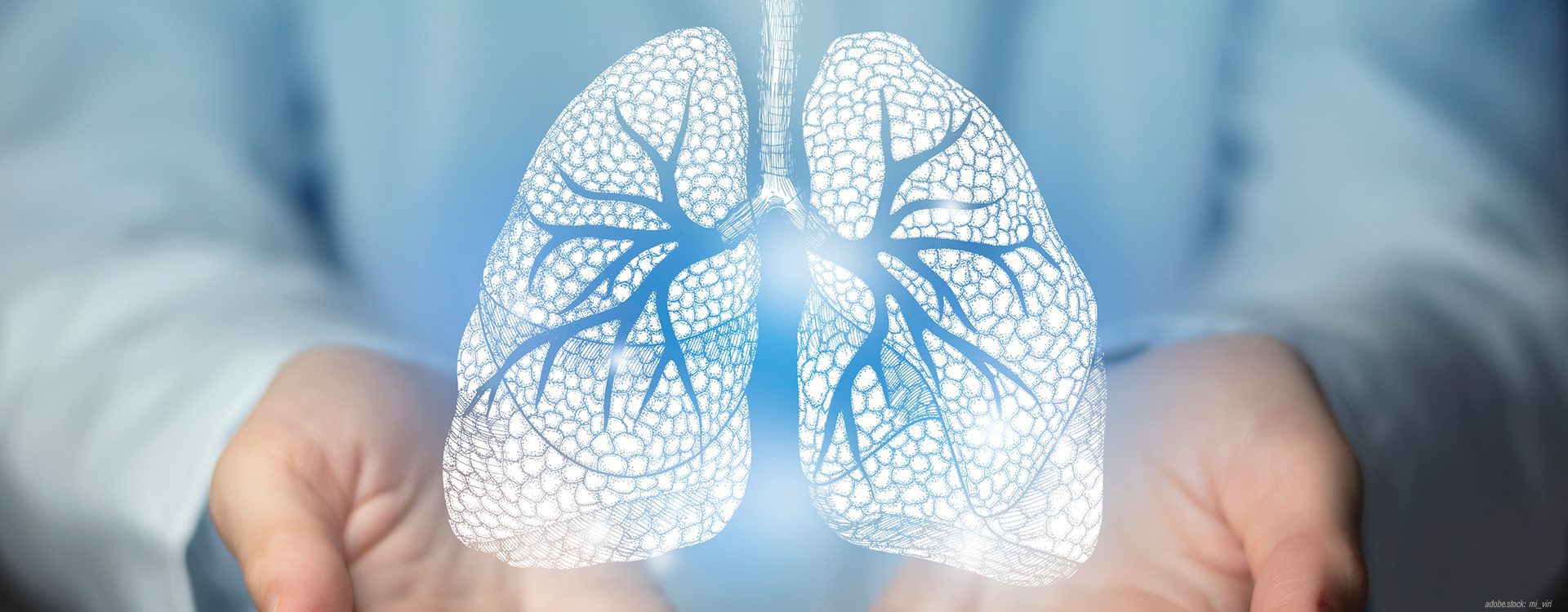 Person in Krankenhausarbeitskleidung zeigt mit der rechten Hand eine abstrakte, hologramartige der menschlichen Lunge