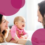 Eine Mutter hält ihr lachendes Baby dem Vater entgegen