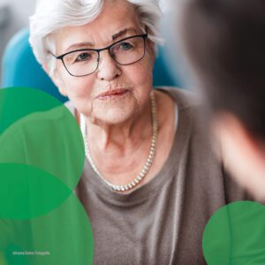 eine ältere Frau mit weißen Harren hört in einem Gespräch aufmerksam zu
