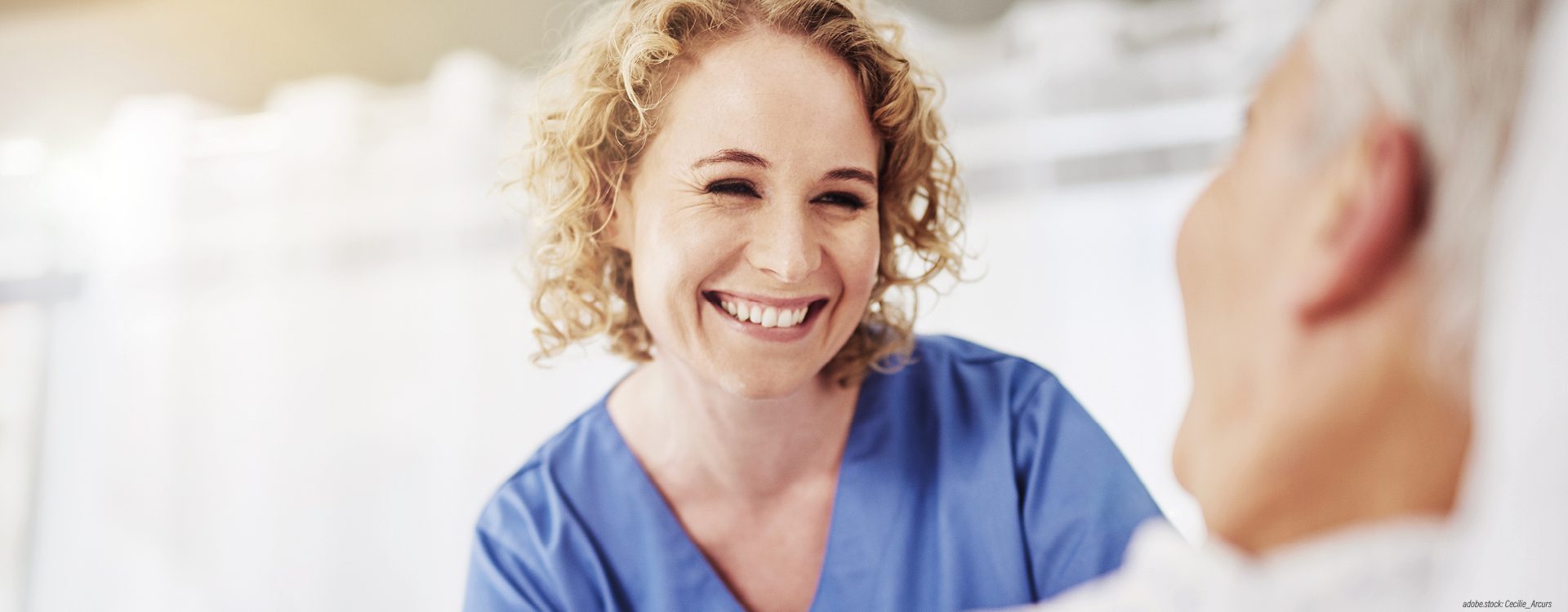 Eine lächelnde weibliche Pflegekraft am Bett einer Patientin