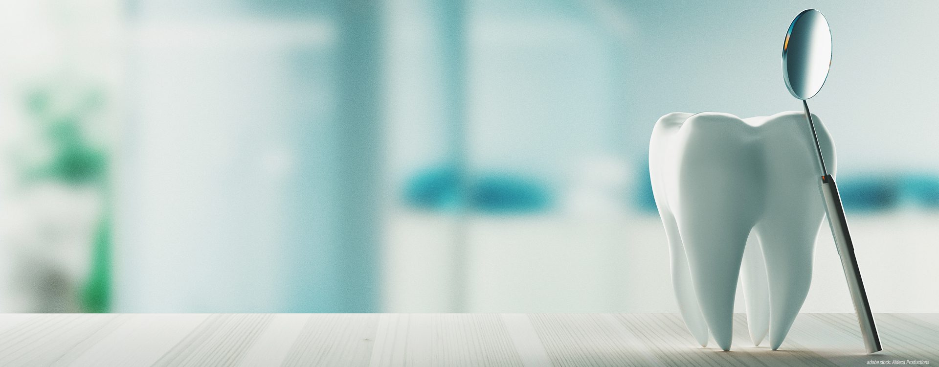 3D-Modell eines Zahns auf einem Tisch. Ein zahnärztlicher Untersuchungsspiegel ist an das Zahnmodell gelehnt.