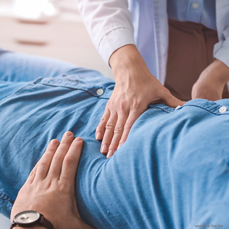 Zwei Hände untersuchen den Bauchbereich eines Patienten